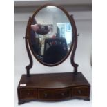 An Edwardian satinwood string inlaid mahogany toilet mirror, the oval plate pivoting on shaped