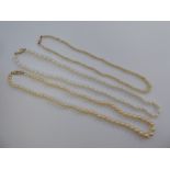 Three single strand pearl necklaces, each on a yellow metal clasp