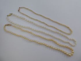 Three single strand pearl necklaces, each on a yellow metal clasp