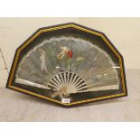An early 20thC fan, decorated with dancing female figures, on mother-of-pearl spines, in a glazed