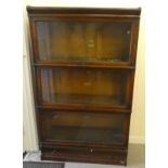 A 1920s/30s oak matched and adapted three section bookcase with lift and slide doors and a base