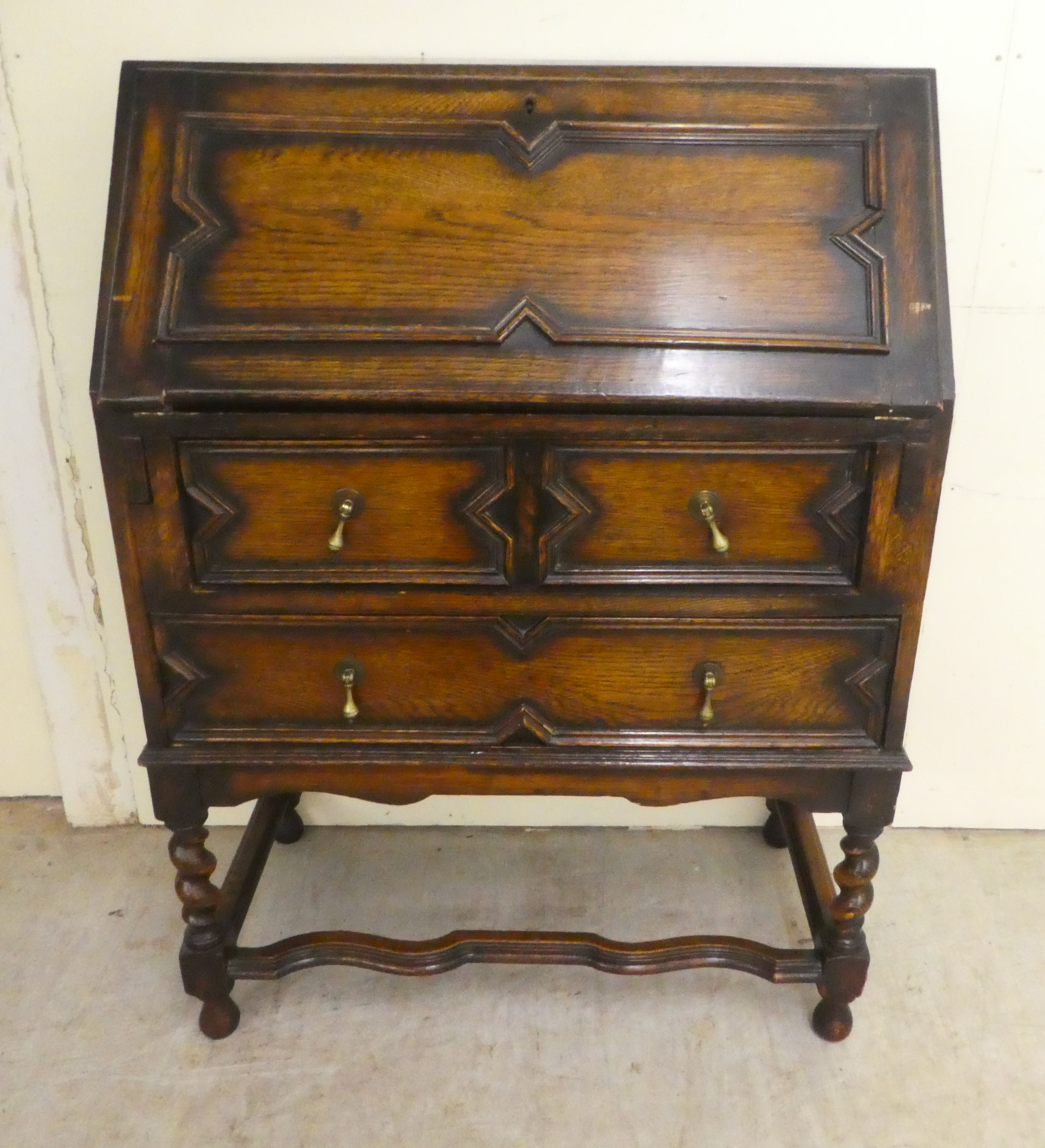 A 1930s oak bureau, the fall flap over two long drawers, raised on barleytwist, block supports  38"h