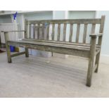 A slatted weathered teak garden bench, raised on square legs  60"w