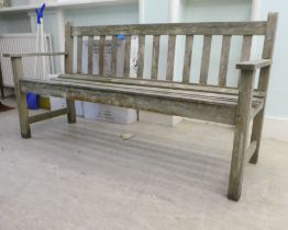 A slatted weathered teak garden bench, raised on square legs  60"w