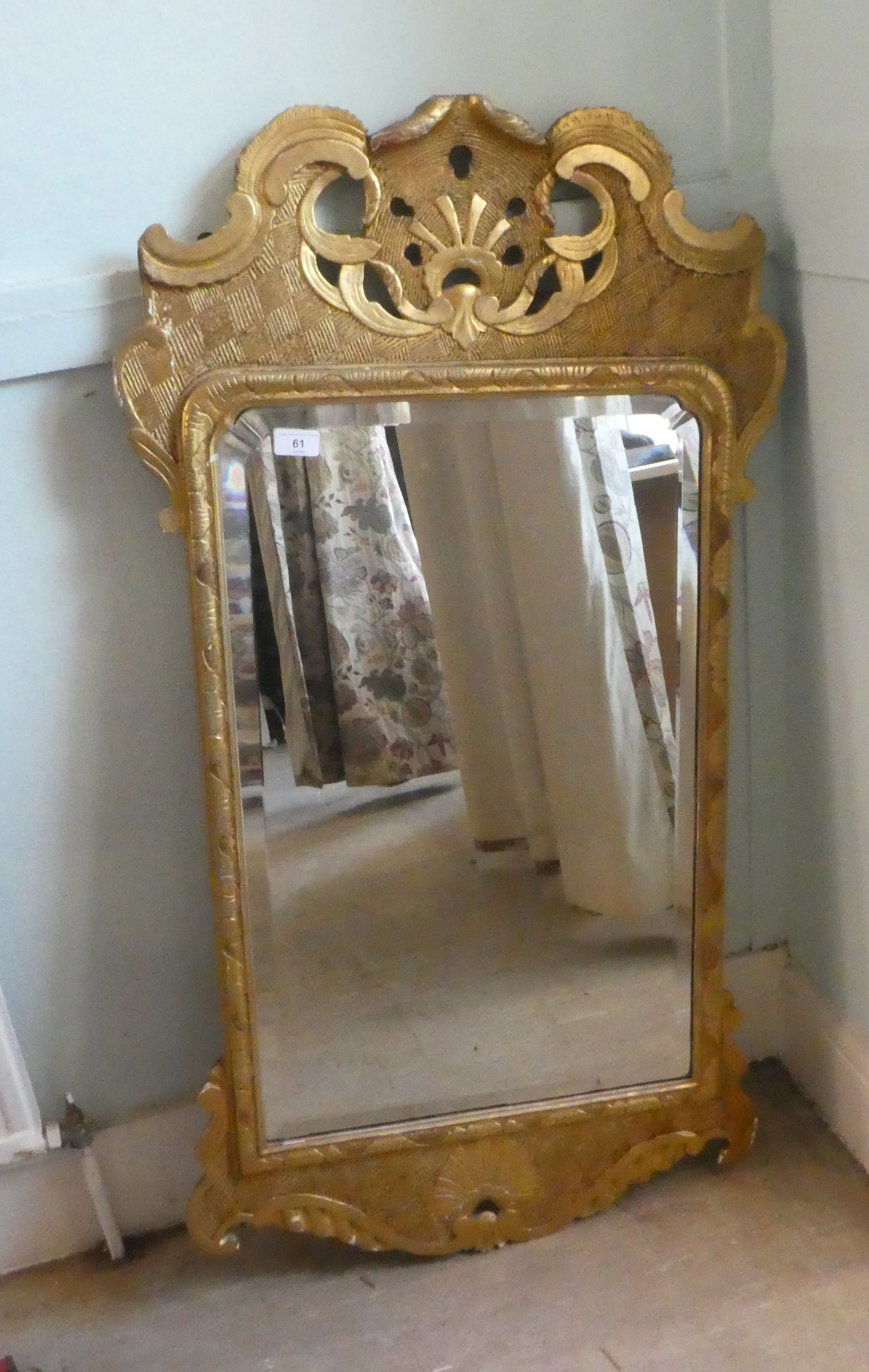 An early 20thC mirror, the shaped, bevelled plate set in a gilded pine frame  44" x 24"