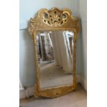 An early 20thC mirror, the shaped, bevelled plate set in a gilded pine frame  44" x 24"