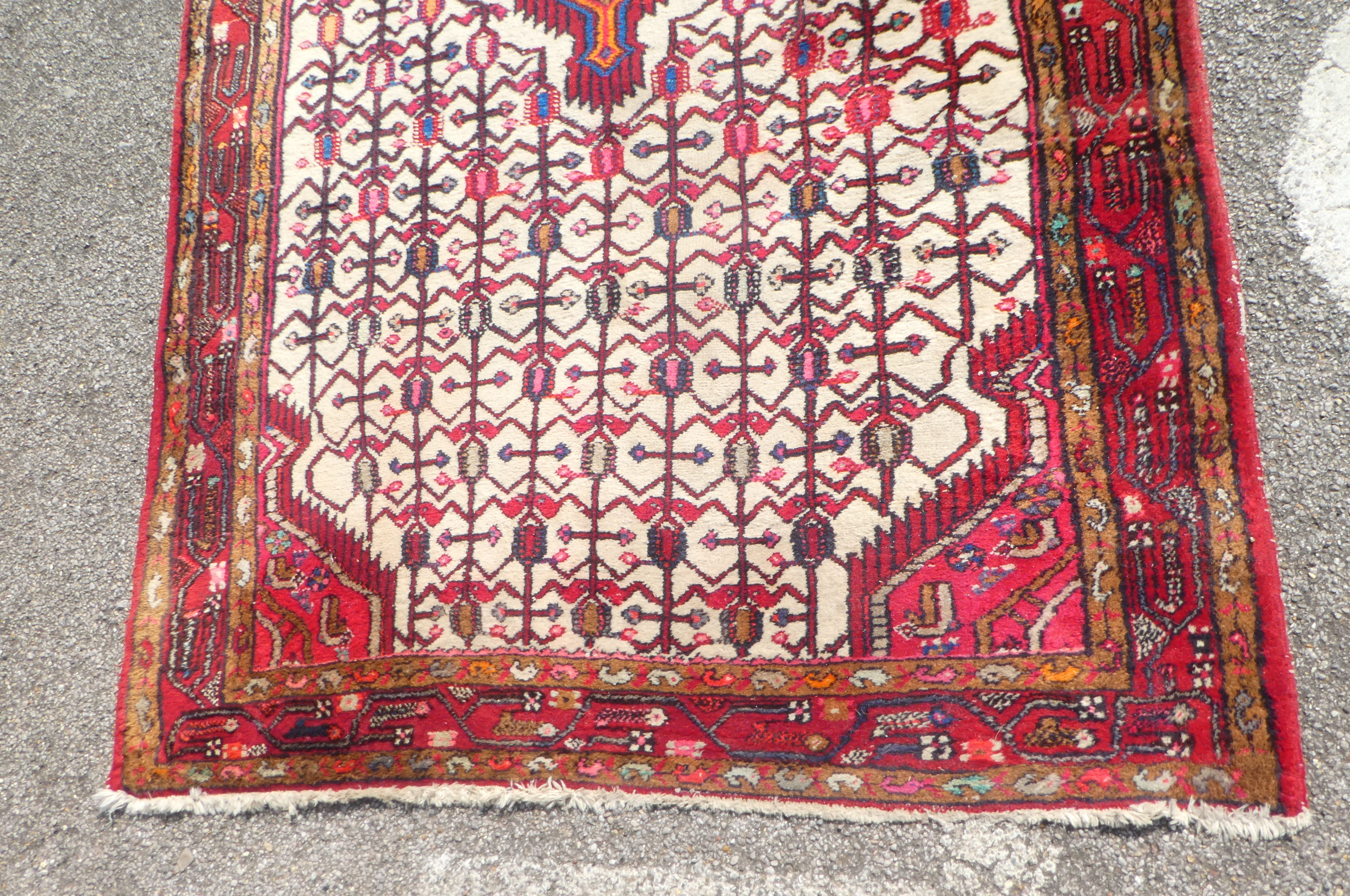 A Persian rug with a central motif, bordered by repeating stylised designs, on a multi-coloured - Bild 3 aus 4