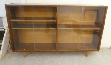 A 1970s teak, glazed front bookcase, raised on tapered legs  32"h  54"w
