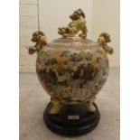 An early 20thC Japanese Satsuma earthenware vase of spherical form, surmounted by dragons, decorated