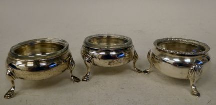 A pair of early 19thC silver salt cellars of shallow ogee form, elevated on hoof feet with glass