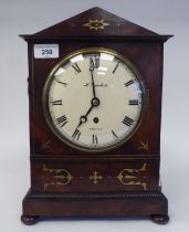 A Regency mahogany and inlaid brass cased mantel timepiece with a pointed arch top, on bun feet; the