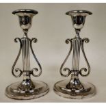 A pair of loaded silver lyre design candlesticks of oval outline, each with a detachable sconce