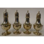 A set of four Edwardian silver pedestal pepper pots with domed covers and flame finials  Chester