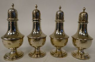 A set of four Edwardian silver pedestal pepper pots with domed covers and flame finials  Chester