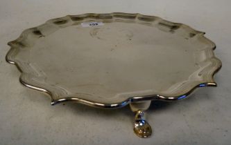 An Edwardian silver salver with a raised piecrust border, elevated on hoof feet  HE & Co  London