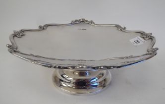 A silver tazza with a cast and applied, scrolled border, elevated on a domed footrim  Henry Atkin