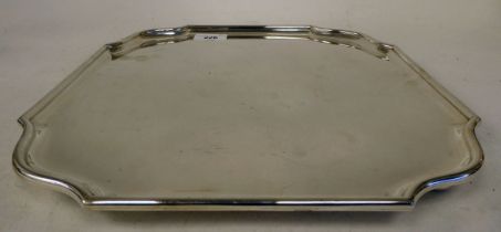 An Edwardian silver salver with a raised piecrust border, elevated on bun feet  HE & Co  London 1910