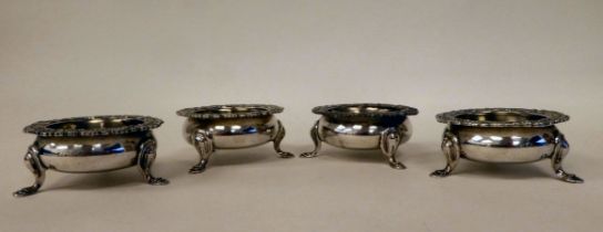 A set of four Edwardian silver salt cellars of ogee form with flared, foliate and shell cast rims,