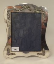 An Edwardian silver framed and glazed photograph frame of incurved outline, overlaid in cast, ribbon