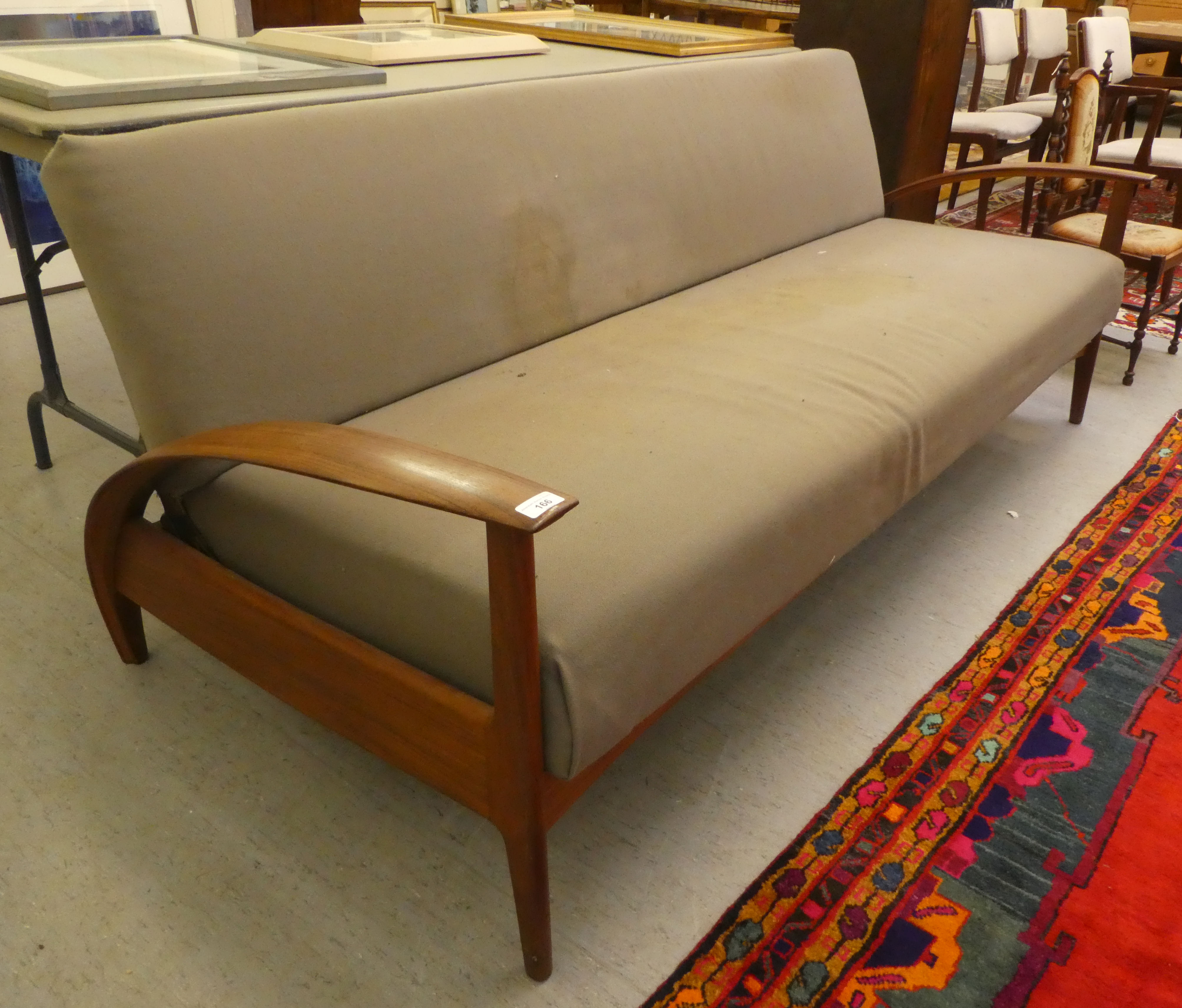 A 1970s teak framed bed settee, raised on a panelled underframe and turned legs   bears a