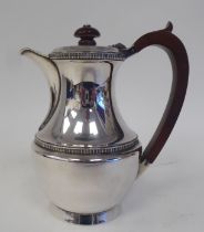 A silver tall hot water pot of waisted bulbous form with border decoration, an insulated handle