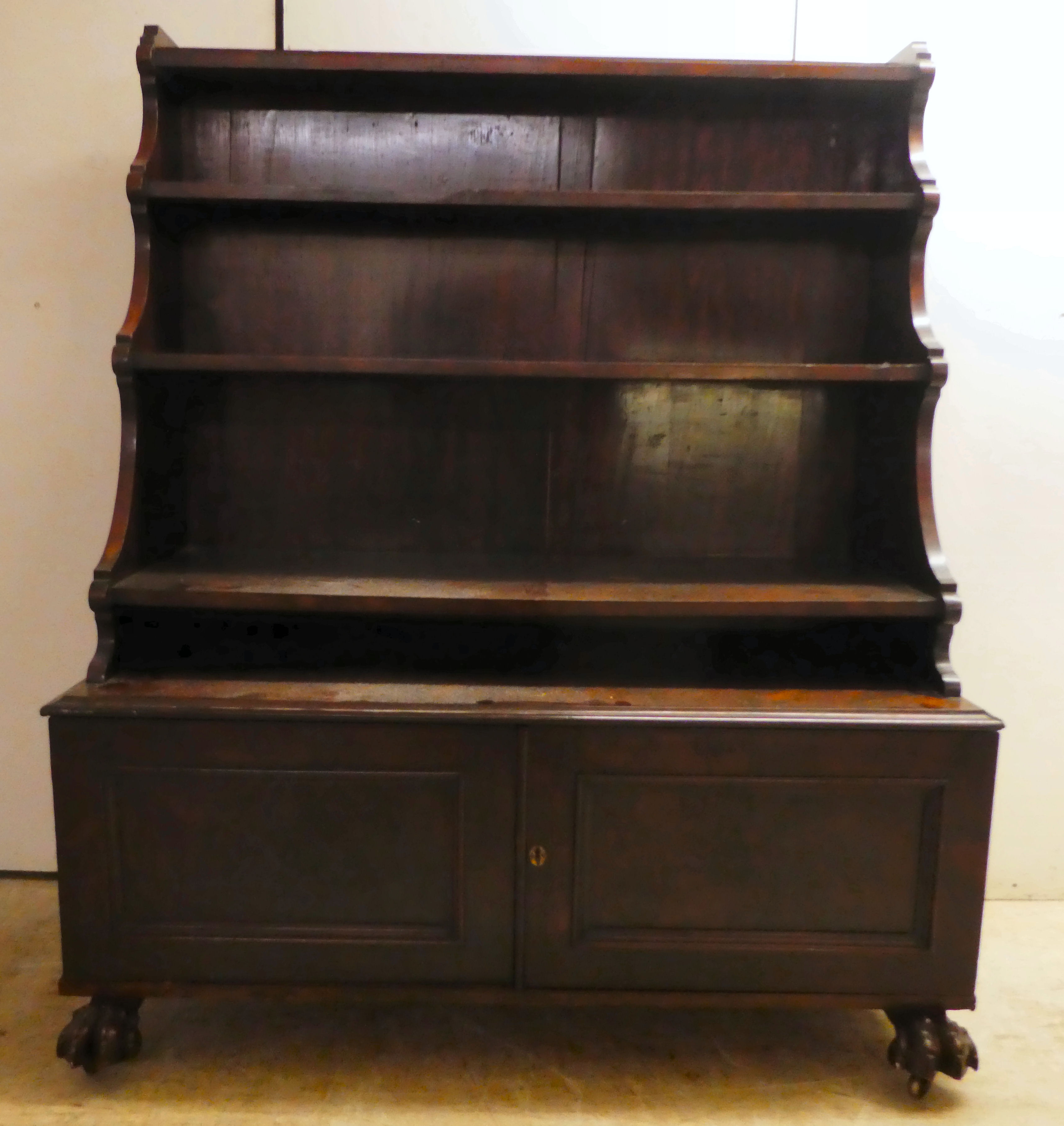 An early 19thC mahogany waterfall front bookcase with three tiers, over two panelled doors, on a