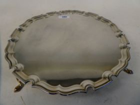 An Edwardian silver salver with a raised piecrust border, elevated on pad feet  The Goldsmith Co,