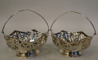 A pair of Edwardian silver pedestal sweet baskets with swing handles  London maker's marks rubbed