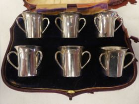 A set of six Edwardian silver tot cups, each fashioned as a miniature, triple handled tyg with a