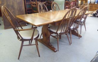 An Ercol Golden Dawn beech and elm draw leaf dining table with a panelled top, raised on shaped