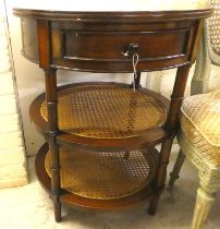A modern mahogany finished occasional table with a frieze drawer, over two caned platforms, raised