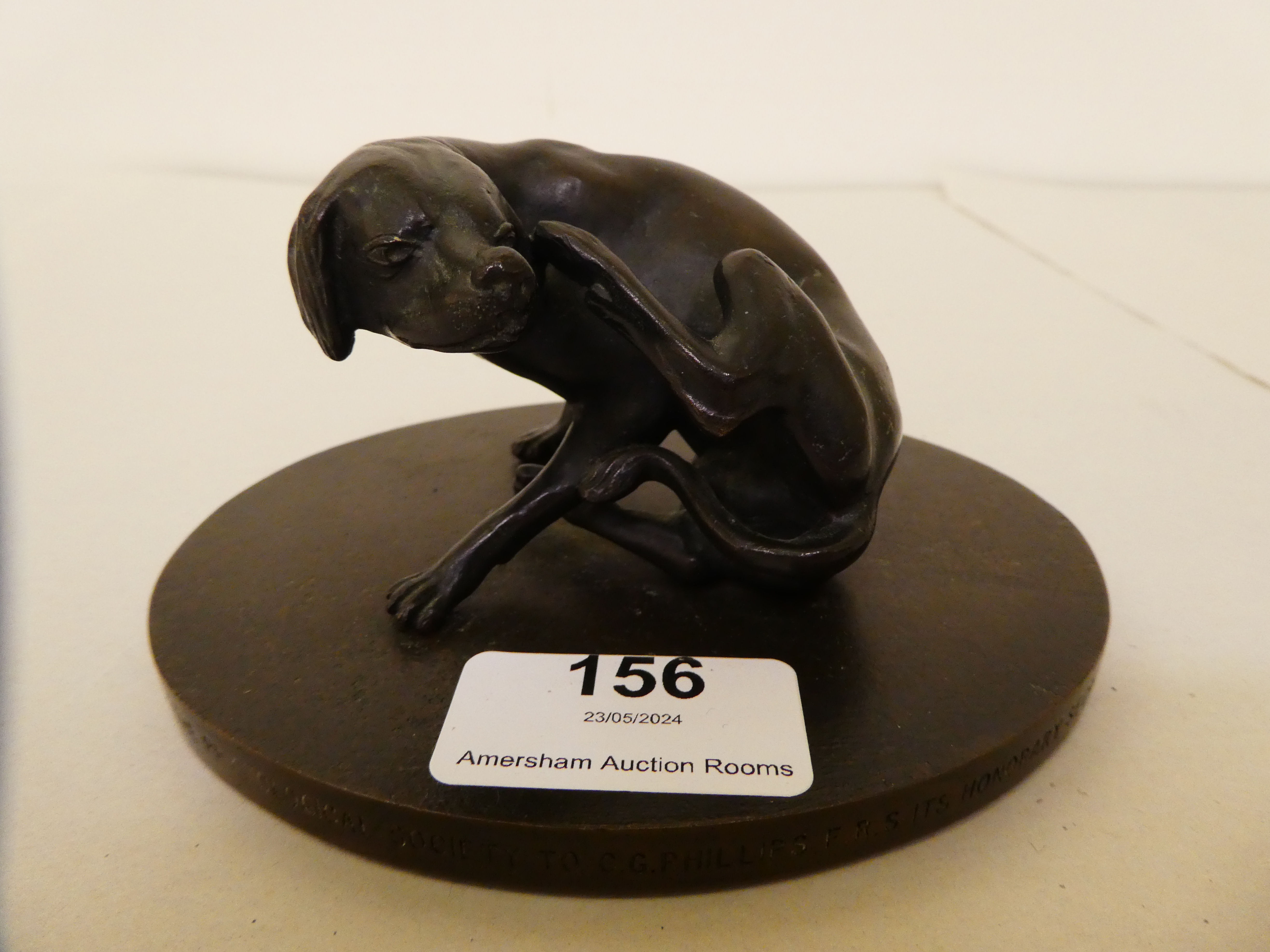 A 1960s cast and patinated bronze model, a seated hound, scratching its ears  3.5"h
