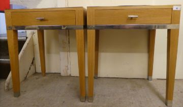 A pair of modern light oak lamp tables, each with chrome trim and a drawer, raised on square legs