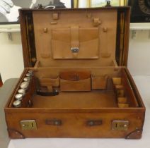 A gentleman's stitched brown hide vanity case, the hinged lid enclosing a fitted interior with