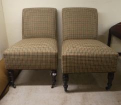 A pair of modern bedroom chairs, each upholstered in a chequered fabric, raised on turned legs