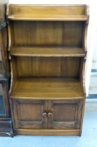 An Ercol Golden Dawn beech and elm waterfall front, two tier bookcase, over a pair of panelled doors