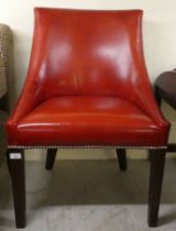 A modern cherry red leather upholstered desk chair, raised on oak square, tapered legs
