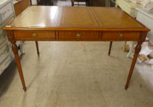 A modern mahogany desk, the top set with a tooled brown hide scriber, over three drawers, raised