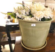 A green glazed stoneware planter  16"h  19"dia containing an arrangement of silk flowers