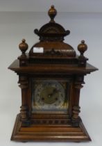 A late 19th/early 20thC walnut cased mantel clock with a domed top, turned finials and flank