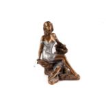 A bronzed figure of a lady sitting on the rocks