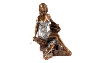 A bronzed figure of a lady sitting on the rocks