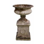 A decorative stone composite garden urn on plinth