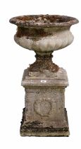 A decorative stone composite garden urn on plinth