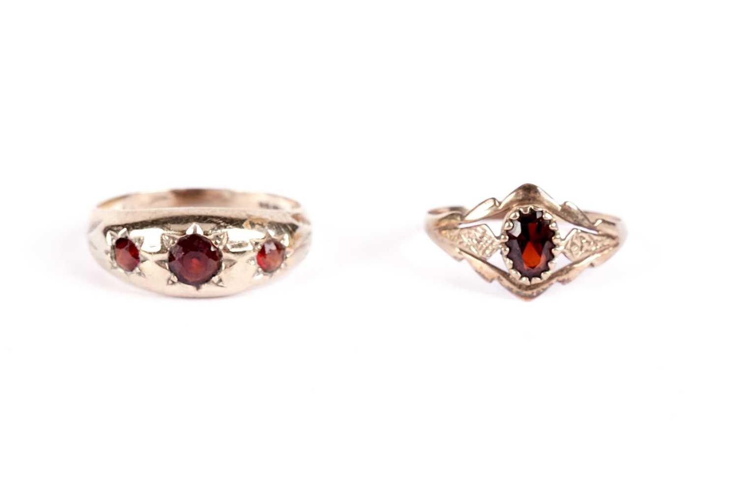 A garnet three stone band; and another garnet ring