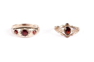 A garnet three stone band; and another garnet ring