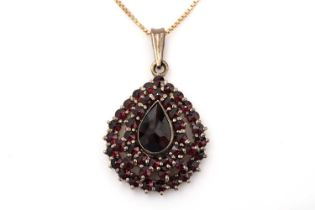 A garnet and yellow metal cluster pendant on chain