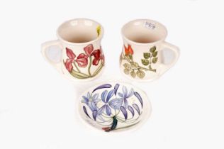 Two Moorcroft ceramic mugs, and a Moorcroft pin dish
