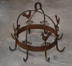 A wrought iron crown-shaped cooking pan rack, embellished with cockerels, 32 cm high x 38 cm diam