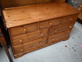 A modern stained pine seven drawer chest with turned handles, 134 cm wide x 45 cm deep x 78 cm high